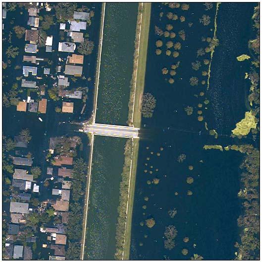 Post flood aerial image showing inundated zones on either side of a drainage canal.