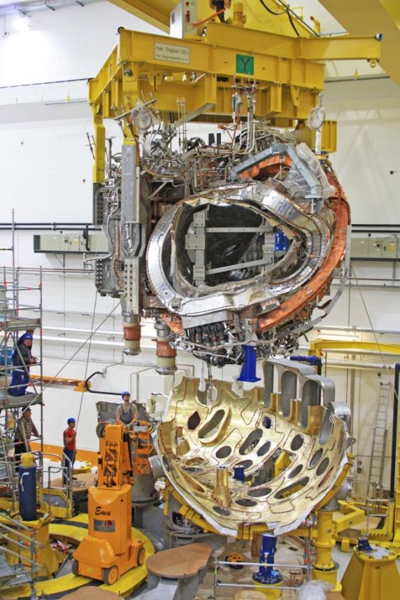 Huge masses must be exactly maneuvered into position, with an accuracy that is dictated by stellarator physics. Then the upper part of the cryostat vessel is installed.