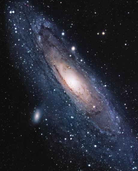 M31 has about twice as many stars as our Milky Way and a larger visible disk, but it lacks spiral arms. The satellite galaxies M32 and M110 are to M31 s upper center and lower left.