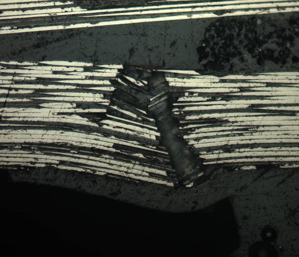 100 m Figure 2.6: A micrograph from the experimental study in Paper C, which shows a kinkband out-of-plane for a fibre tow. A resin rich region can be seen above this kinked fibre tow.