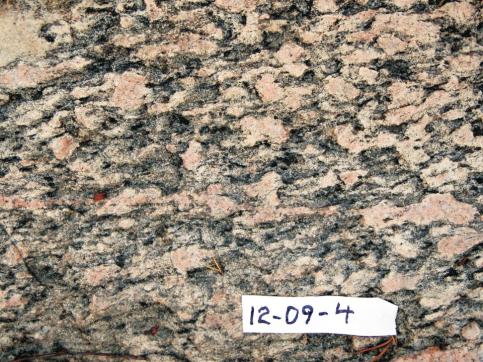 greywacke (pale) to mudstone (darker) with tops shown as arrows; d) quartz monzonite with variably deformed K-feldspar phenocrysts.