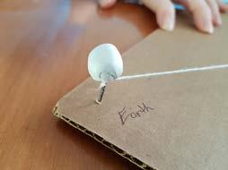 Build a scale model of the Earth-Moon system using a piece of letter-sized piece of cardboard with two pins or nails inserted at opposite corners of the cardboard.
