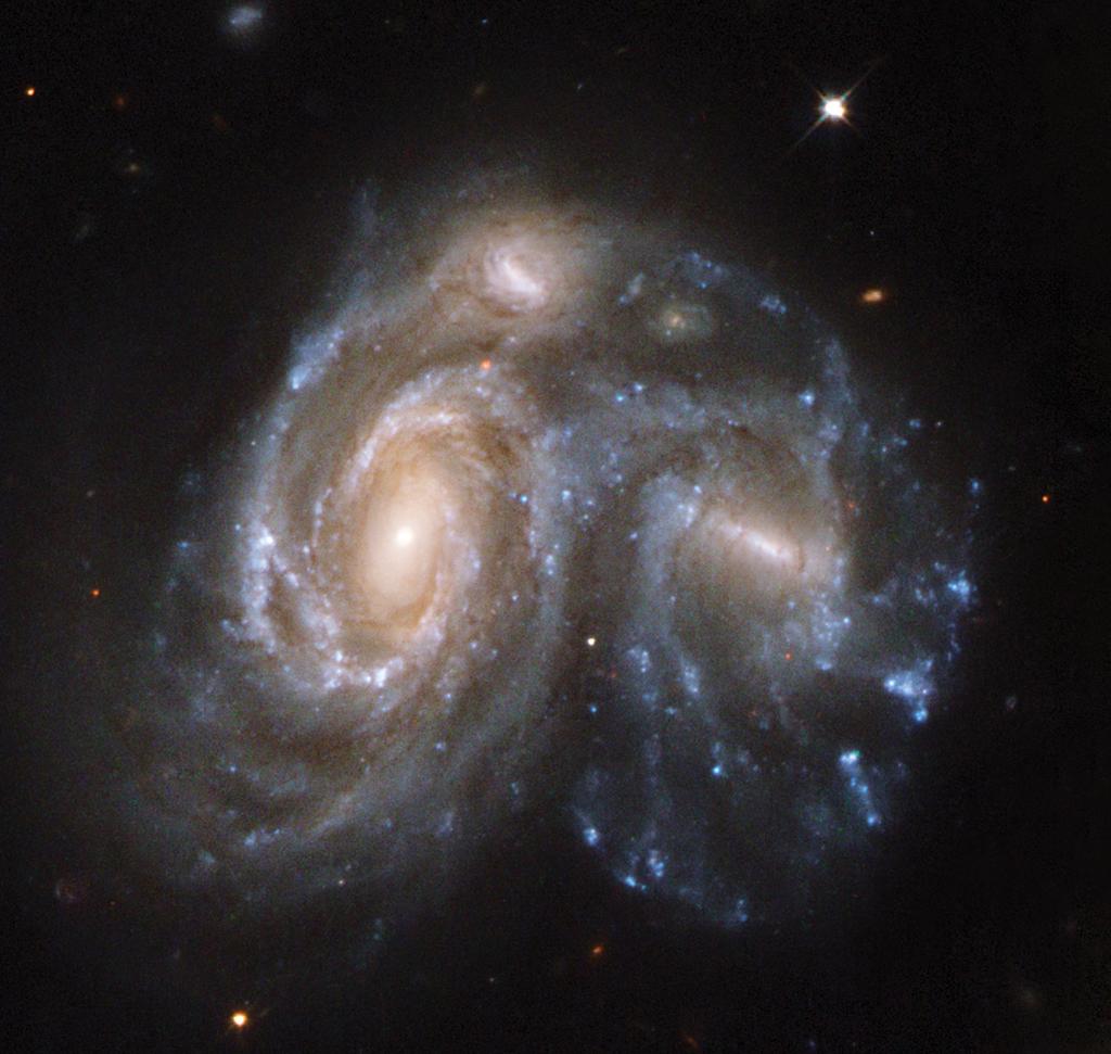 As the galaxy cores approach each other, their gas and dust clouds are buffeted and accelerated dramatically by the conflicting pull of matter from all directions.