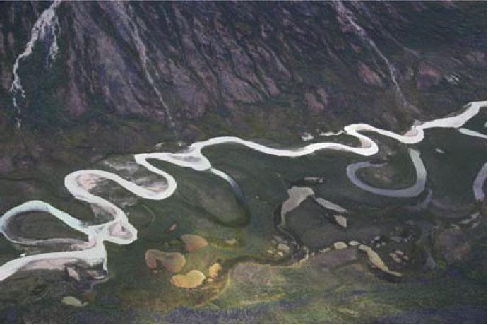 Figure 5. Example of a meandering stream. Note the abandoned loops ( oxbows ) of the stream. Figure 6. Labeled meanders in a stream showing the (sand) point bars and cutbanks.