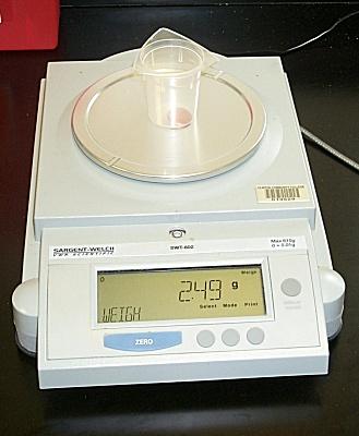 Place a small beaker on the pan of the scale and zero it by pressing down on the zero (tare) button