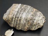 Gneiss: a metamorphic rock displaying gneissose structure. Gneisses are typically layered (also called banded), generally with alternating felsic and darker mineral layers.