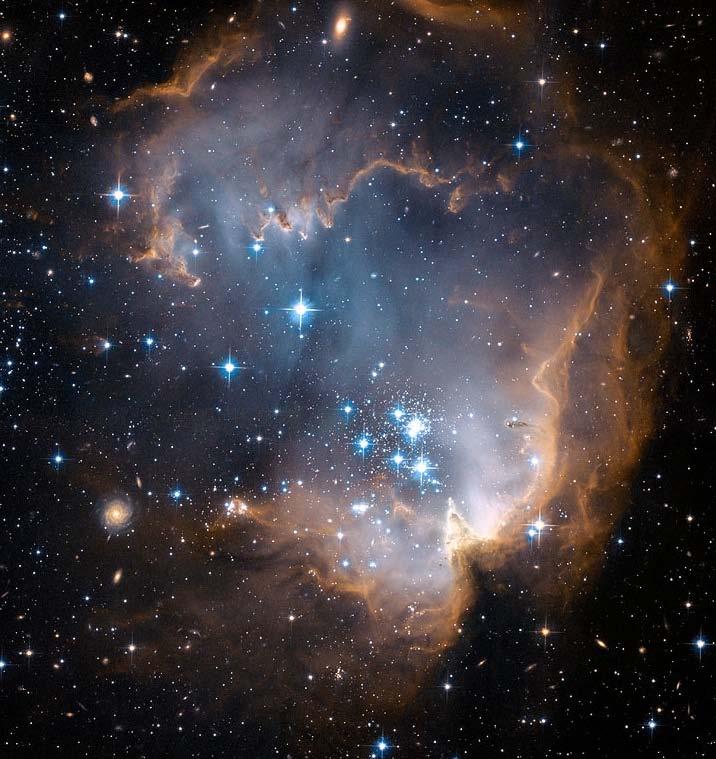 NGC 602 and Beyond, This Hubble Space Telescope image also captures bright, blue, newly formed stars that are blowing a cavity in the center of a young star-forming region only this time near the