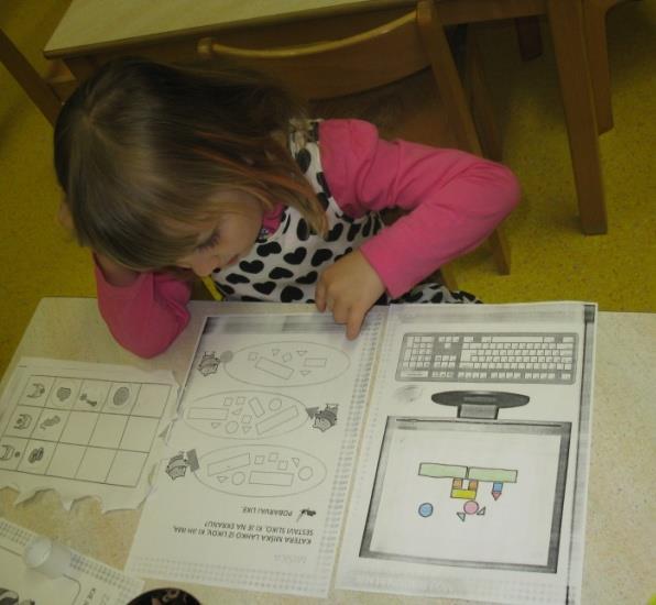 Slika 13: Deklica pri reševanju matematične naloge z geometrijskimi liki.