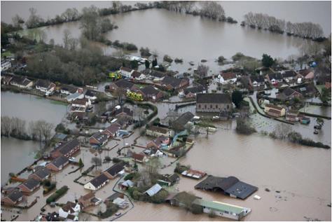 Explain the likely economic effects of river flooding on the area shown in the photograph.