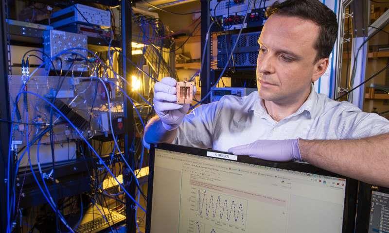 Daniel Bowring holds up a component for detecting dark matter particles called axions.