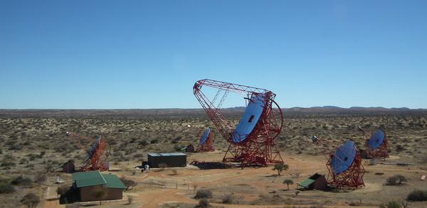 Figure 1.2: The H.E.S.S. telescope array with all five telescopes. Four small telescopes in a square formation with the larger telescope in the middle. be detected on the ground.