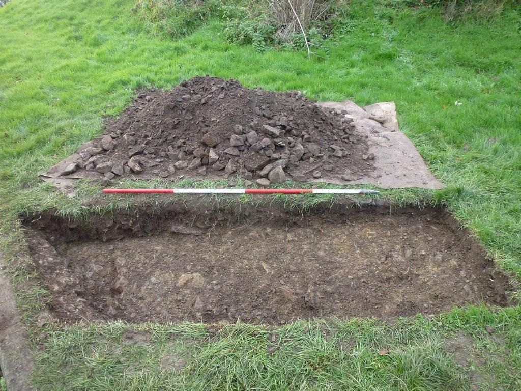 Figure 6: Trench 1B following excavation of dumped-deposit of quarried stone in greyish-brown, silty clay loam soil matrix (123), showing concrete footing for kerb of car park (125) and truncated