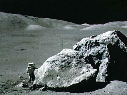 Apollo 17 astronaut Harrison Schmitt standing next to boulder