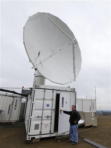 Research scientist Matt Wingo views live radar precipitation data on his mobile phone as he monitors a radar dish located at the Quinault National