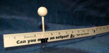 Here are smaller versions of the Earth and Moon (hold up 1 ball for Earth and 1/4 bead for Moon). And here is a yardstick. I ll clip the Earth here at the 4 mark.