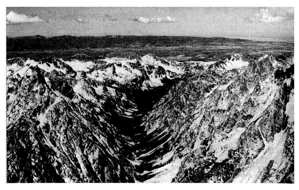 16. Base your answer to the following question on the photograph below, which shows a mountainous region cut by a large