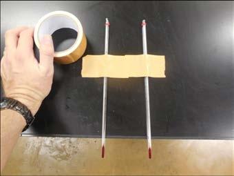 Tape two thermometers to a table with the liquid filled ends hanging