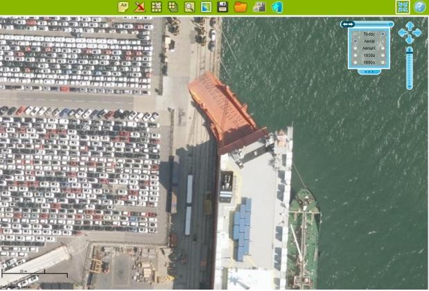 Are the cars being imported or exported? How many cars can you estimate are on the dockside? How many different kinds of boat can be found in these waters? Can you name them?