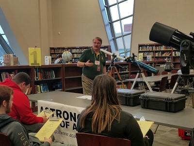 ACA Outreach By Marissa Fanady Lew Snodgrass teaching a group of students about telescopes. Behind him are some examples of the different types. Image by ACA member Lew Snodgrass.