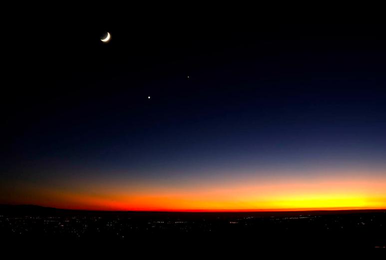 A crescent moon is in the WEST at sunset A
