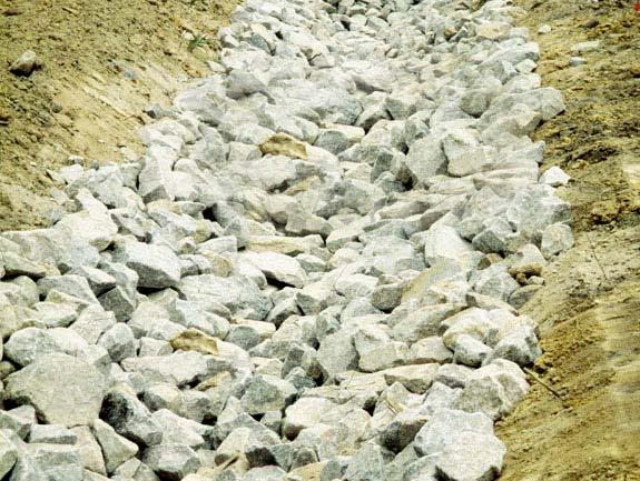 Rock-lined channels and chutes are usually most vulnerable to damage in the first year or two after placement while the voids remain open and