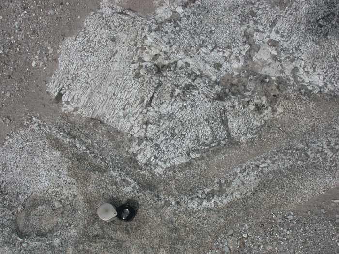 Igneous Rocks Having granite and pegmatite mixed together as in Figure 15, in patches and streaks, indicates dynamic flow of molten rock and fluids during the time the rock was solidifying. Figure 15. The lens is resting on granite, which has relatively small mineral grains the size of sand.