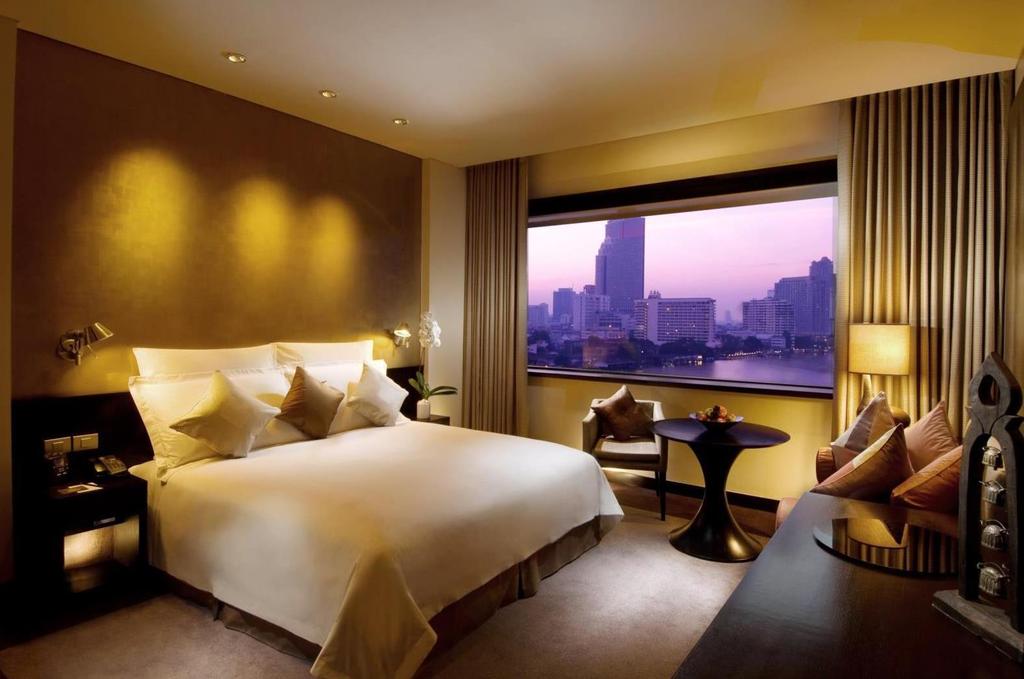 D E L U X E R I V E R V I E W Enjoy breathtaking views of the Chao Phraya River and the city beyond from this room furnished in an elegant contemporary style and featuring a seating area.
