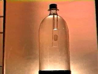 By pressing the sides of the bottle, the pressure within it is increased and the air within the inverted test tube is compressed.