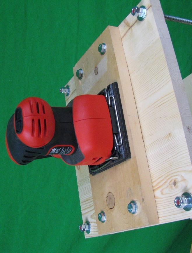 In the present setup, the pad of the orbital sander has been permanently affixed to a thin block of wood with four bolts.