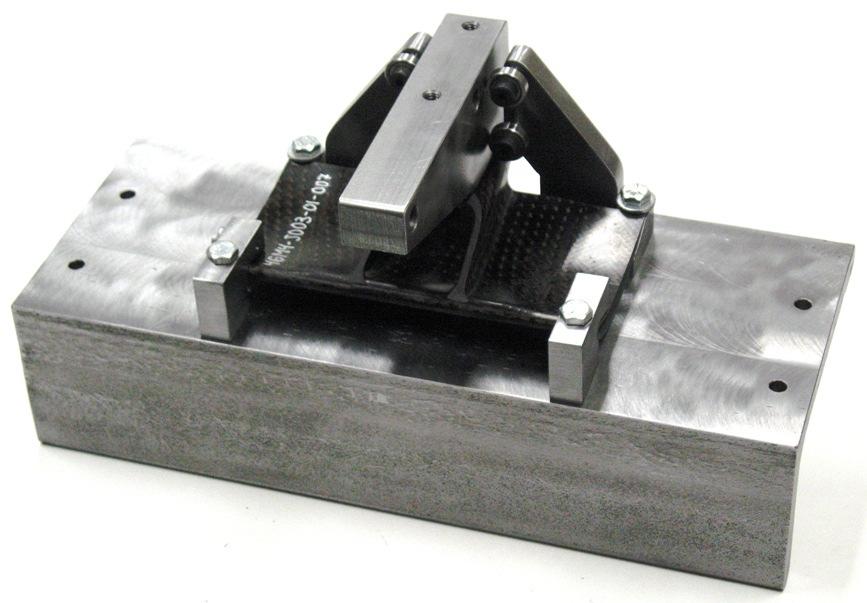 The block is linking the specimen bracket to the MTS test frame through a fixture with bearings sliding in slotted holes.