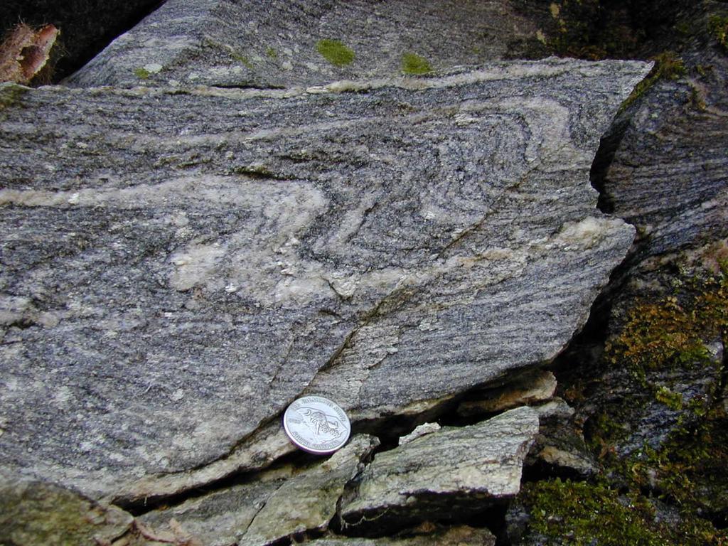 Foliated Textures: Gneissic Gneissic textures occur when the silicate minerals in the rock separate and recrystallize into alternating bands of light (quartz and feldspar) and dark (biotite,
