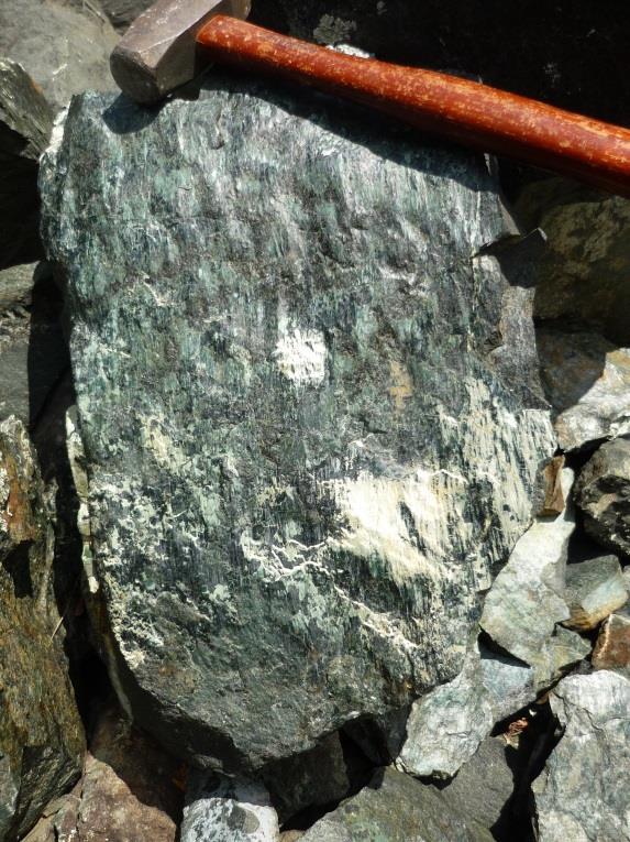 The aligned plates of serpentine impart the waxy sheen to these rock samples. Earth's mantle is thought to be composed mainly of peridotite.