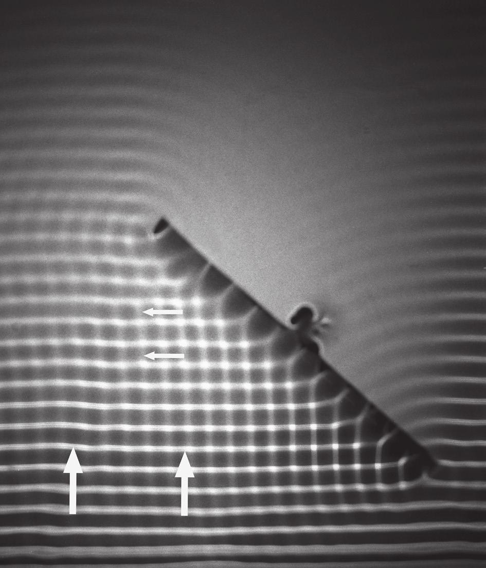 19 (a) Fig. 19.1 shows the image from an experiment using a ripple tank. 18 barrier Fig. 19.1 A straight ruler repeatedly hits the surface of water.