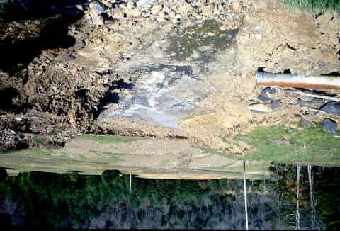 The exposed length of12 inch diameter culvert is approximately 10 feet long. The access road leading to the Dam is visible at the top of the photograph.